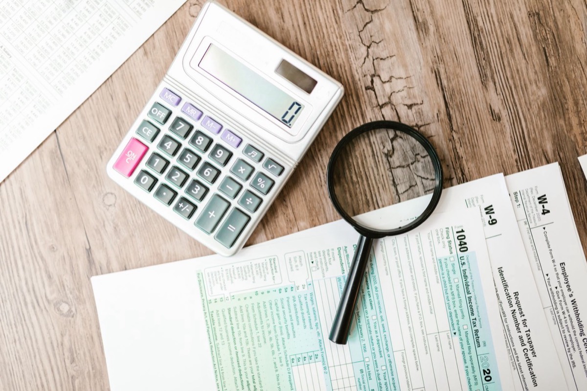 Tax forms, calculator and magnifying glass used to calculate an IRS payment plan for Texas taxpayers owing back taxes